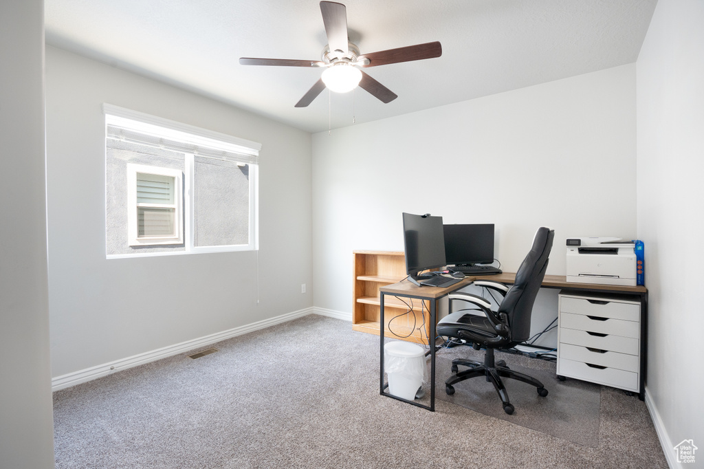 Carpeted office space featuring ceiling fan and baseboards