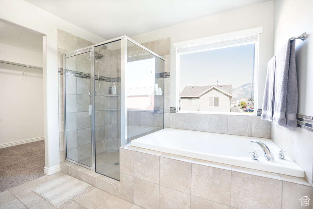 Bathroom featuring a shower stall, a garden tub, tile patterned floors, and a walk in closet