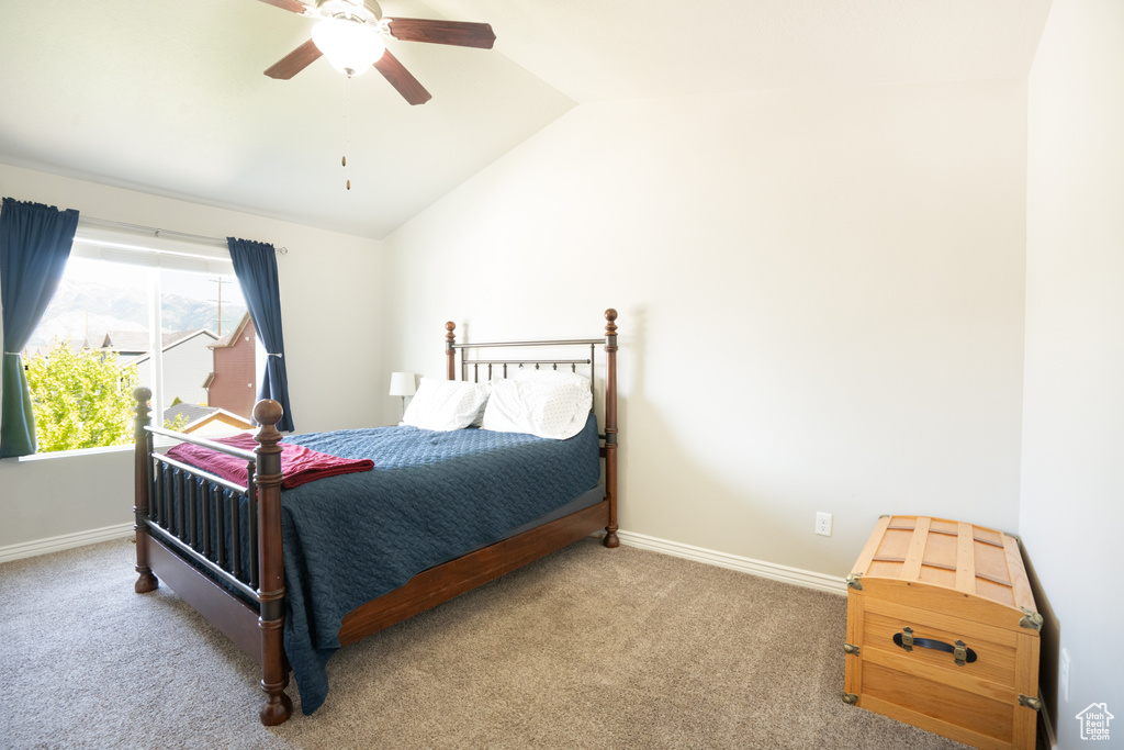 Carpeted bedroom with lofted ceiling, baseboards, and a ceiling fan