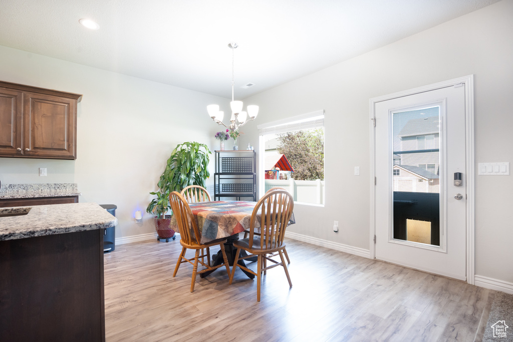 Dining area featuring light wood finished floors, a chandelier, and baseboards