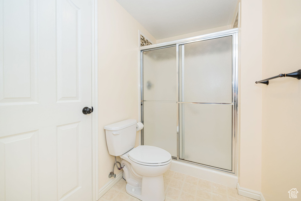 Bathroom with an enclosed shower, toilet, and baseboards