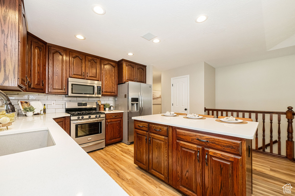Kitchen with stainless steel appliances, a sink, light countertops, light wood-style floors, and recessed lighting