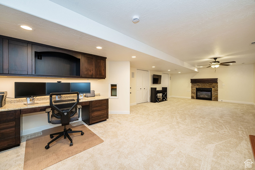 Office space featuring built in study area, light carpet, recessed lighting, ceiling fan, and a fireplace