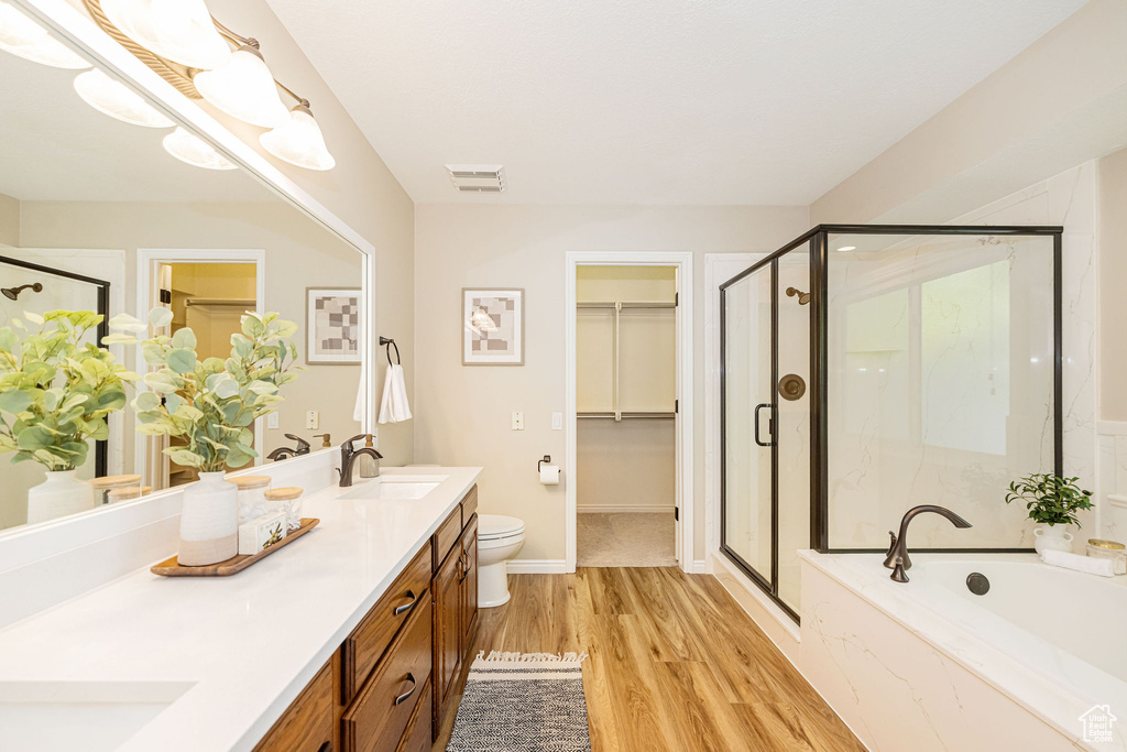 Full bathroom with a shower stall, double vanity, a bath, and wood finished floors