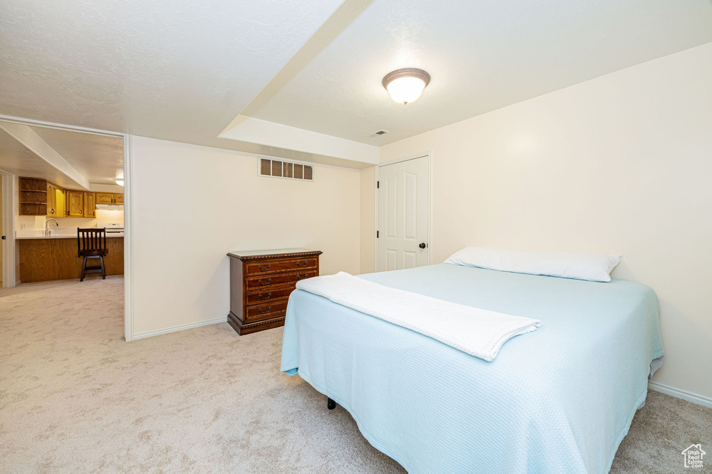 Bedroom featuring light colored carpet, baseboards, and a sink