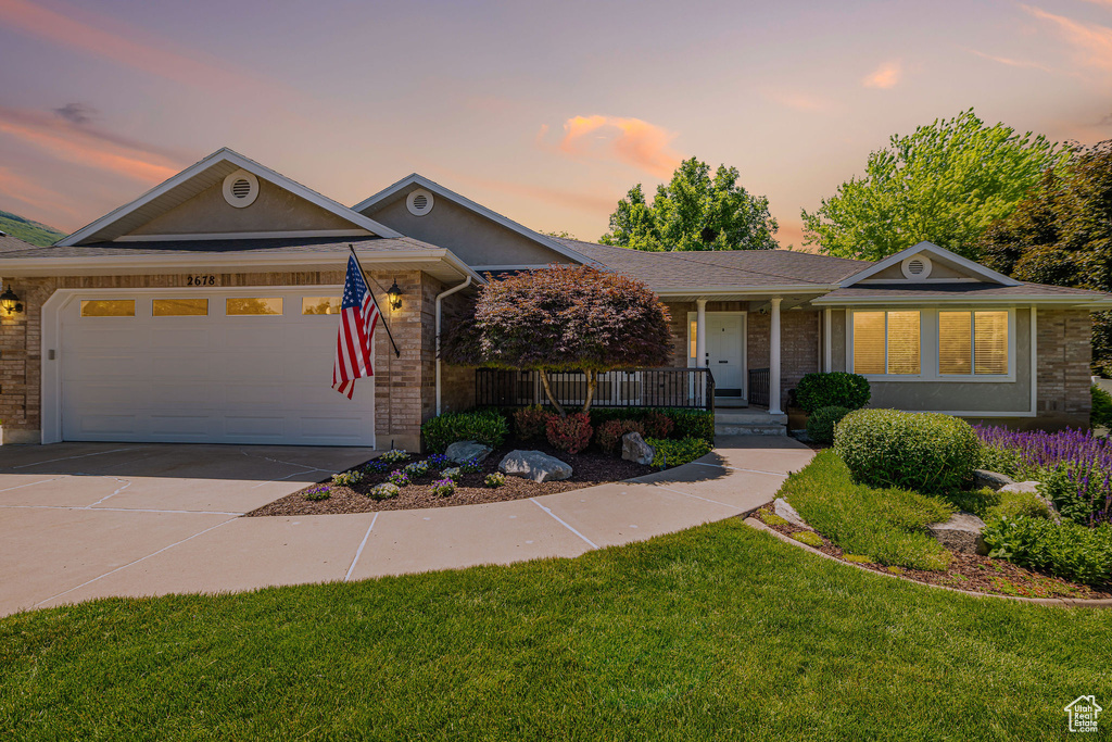 Ranch-style house featuring a porch, concrete driveway, a front yard, a garage, and brick siding