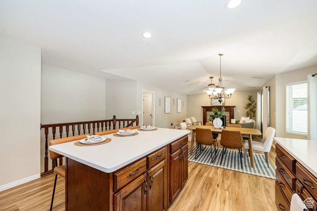 Kitchen with light wood-style flooring, light countertops, a chandelier, a kitchen island, and baseboards