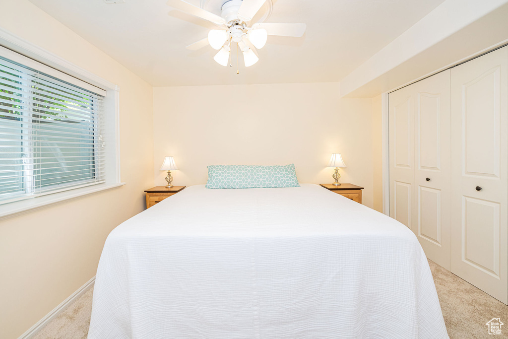 Bedroom featuring light colored carpet, a closet, and a ceiling fan