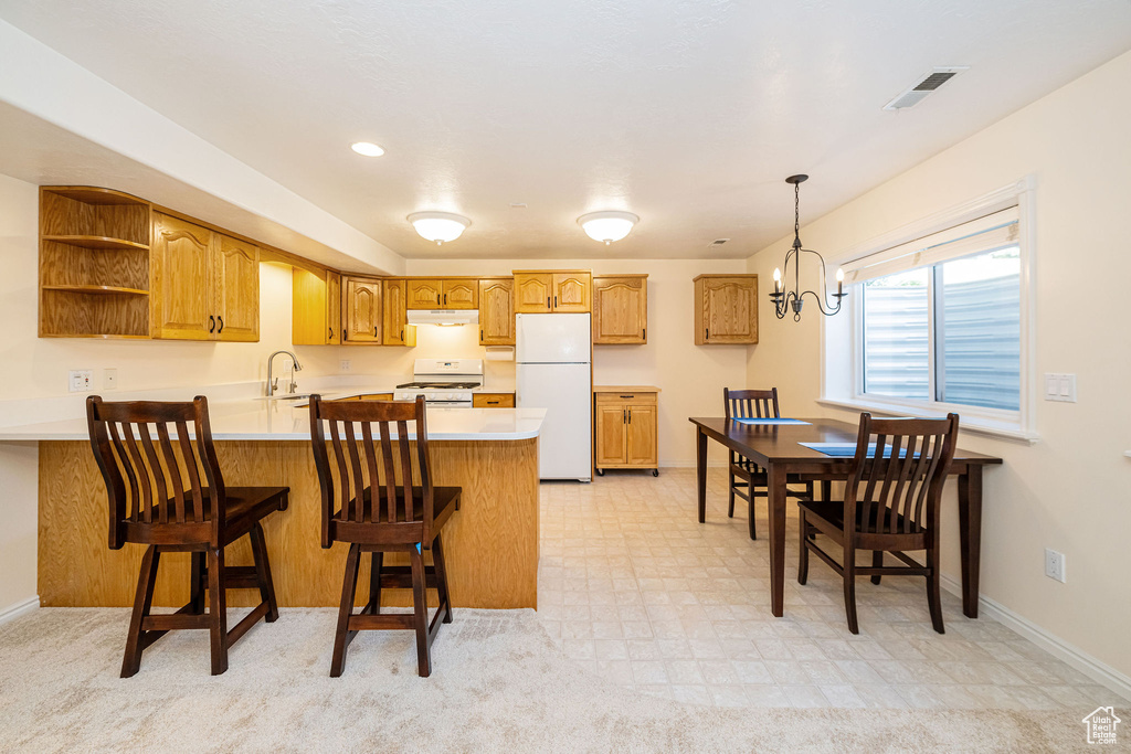 Kitchen featuring white appliances, a peninsula, light countertops, open shelves, and brown cabinets