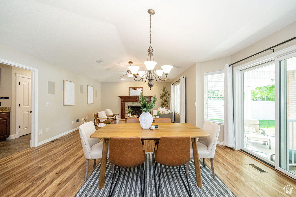 Dining space featuring light wood-style flooring, a chandelier, a stone fireplace, and baseboards