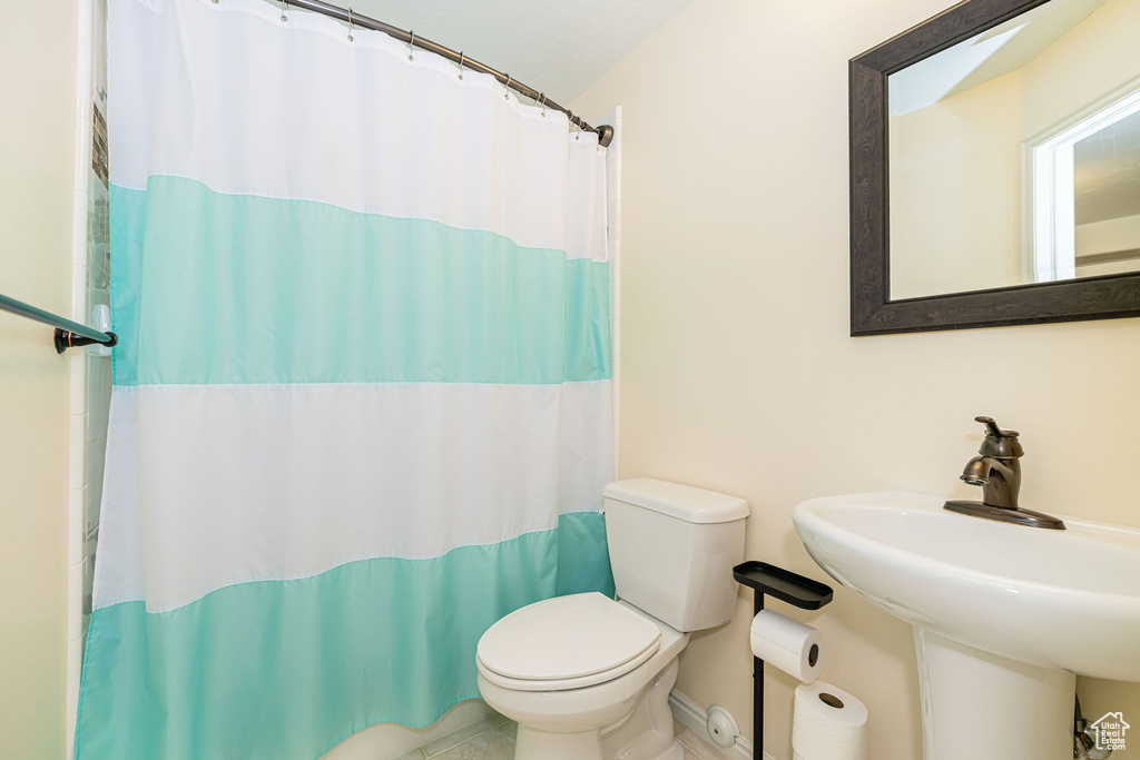Full bath with toilet, a sink, and curtained shower