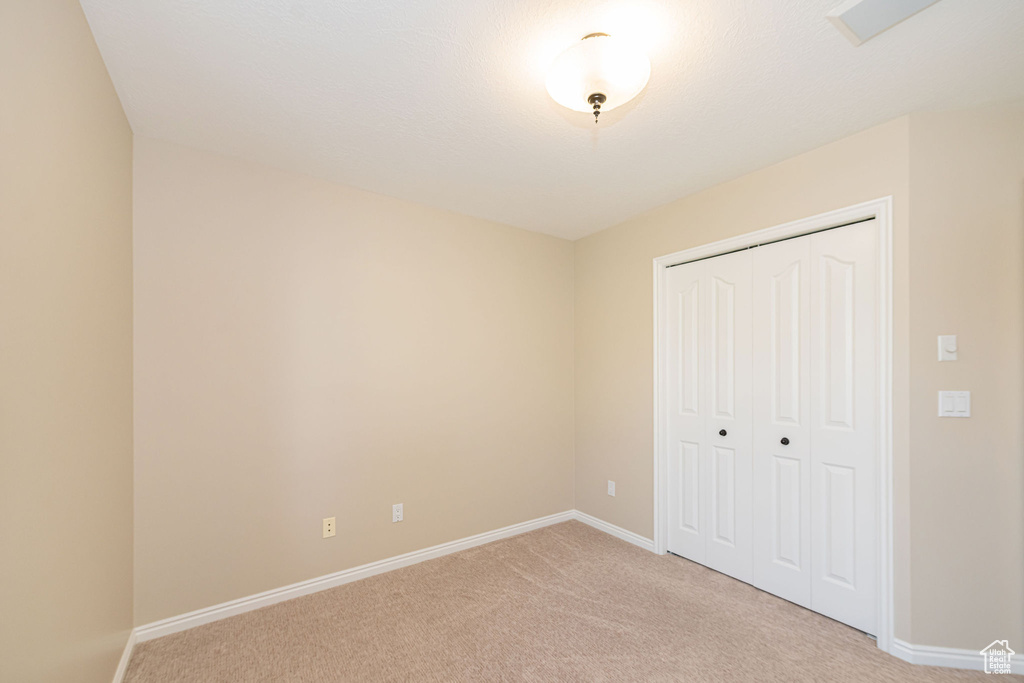 Unfurnished bedroom with light colored carpet, baseboards, and a closet