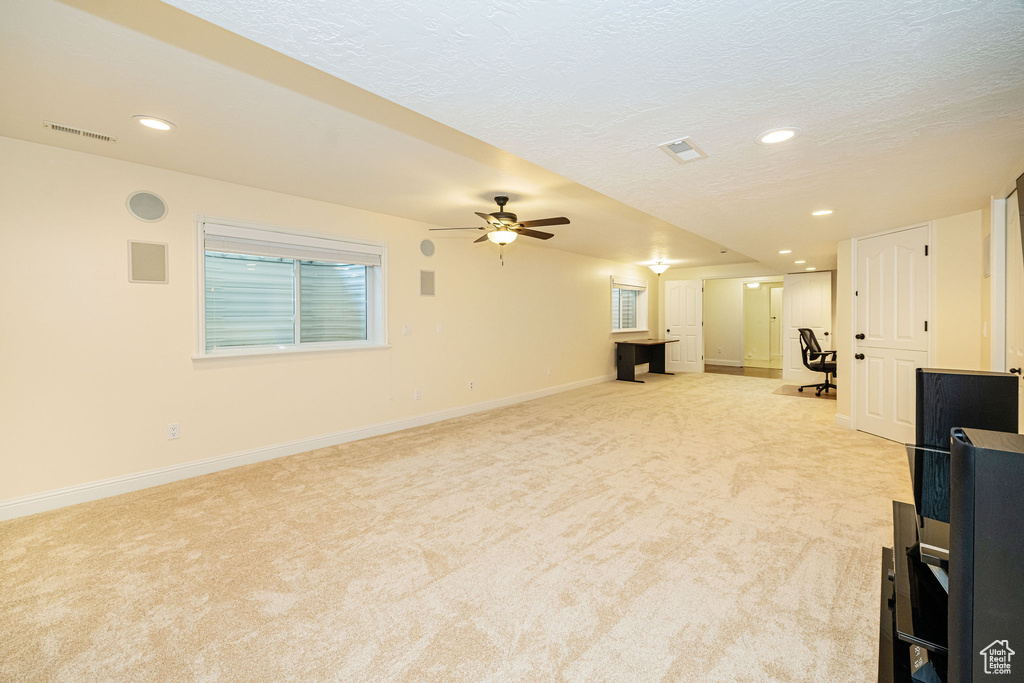 Unfurnished living room featuring light carpet, a ceiling fan, baseboards, recessed lighting, and a textured ceiling