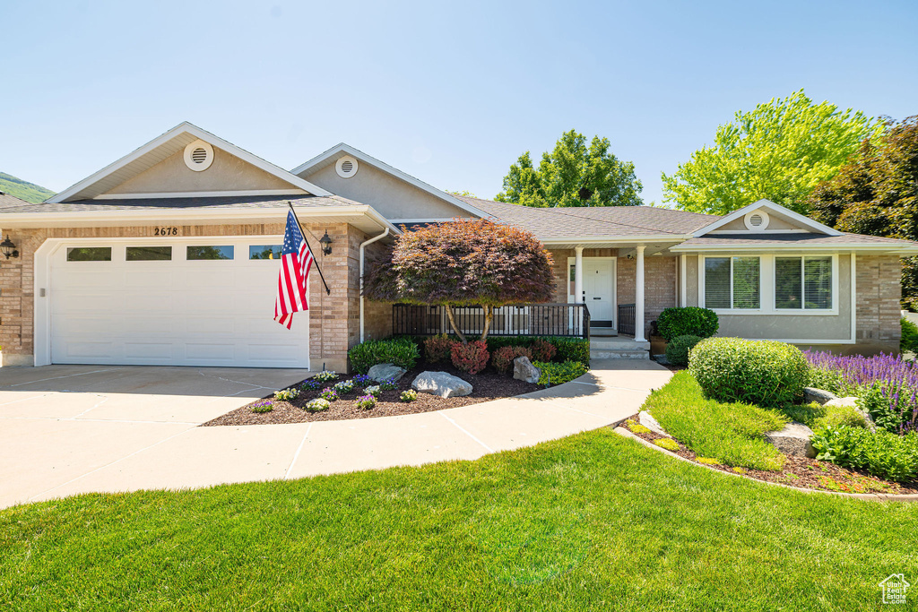 Ranch-style house featuring a garage, a porch, concrete driveway, a front lawn, and brick siding