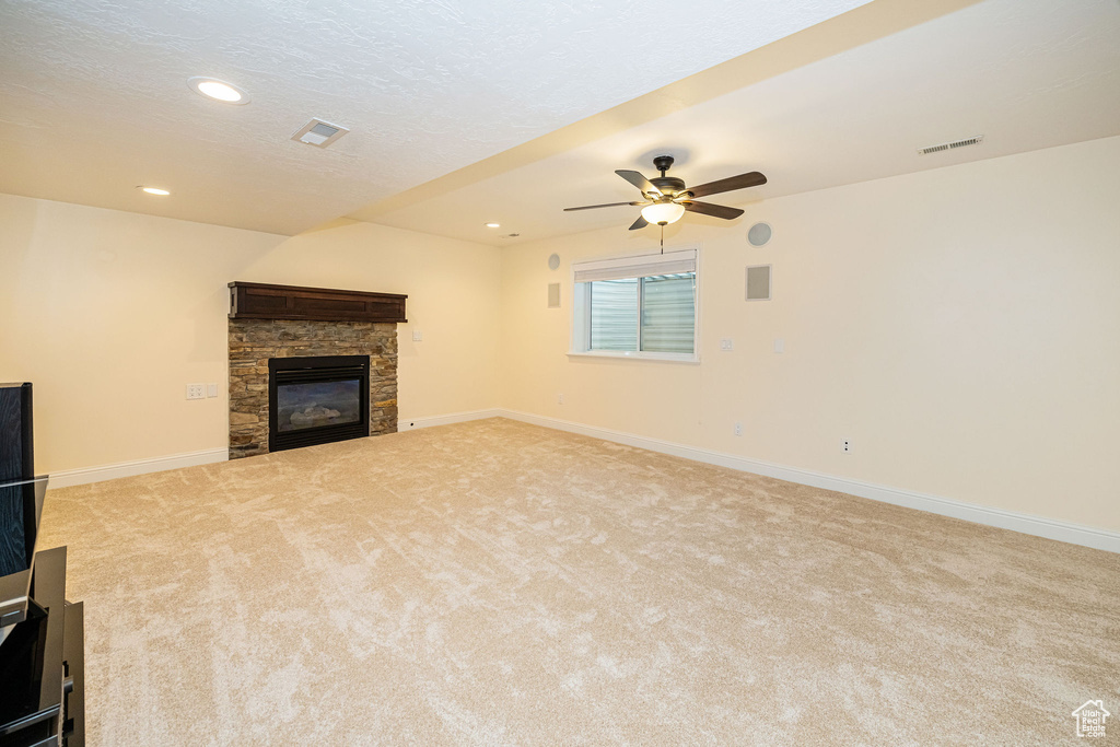 Unfurnished living room featuring a stone fireplace, carpet floors, a ceiling fan, baseboards, and recessed lighting