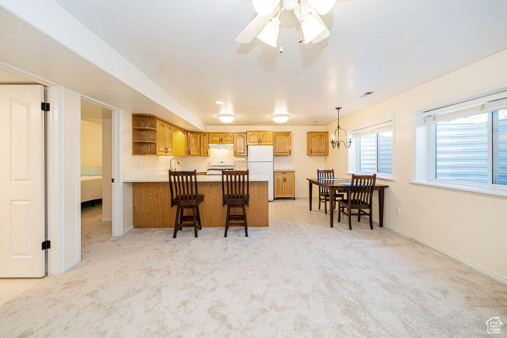 Kitchen featuring a peninsula, white appliances, open shelves, ceiling fan, and a kitchen bar
