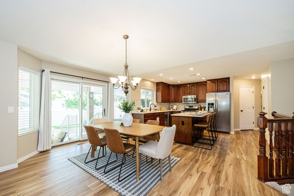 Dining area with light wood-style flooring, a chandelier, baseboards, and recessed lighting