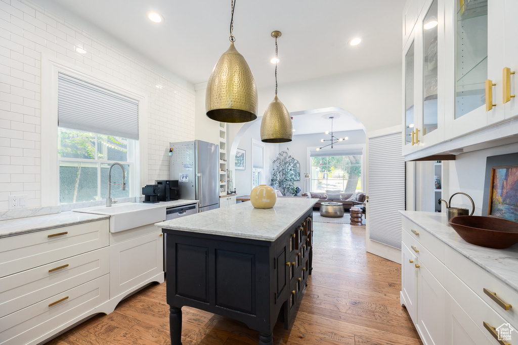 Kitchen featuring a sink, freestanding refrigerator, white cabinets, a chandelier, and a kitchen island