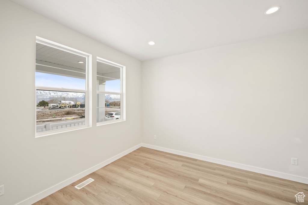 Unfurnished room with baseboards, light wood-type flooring, and recessed lighting