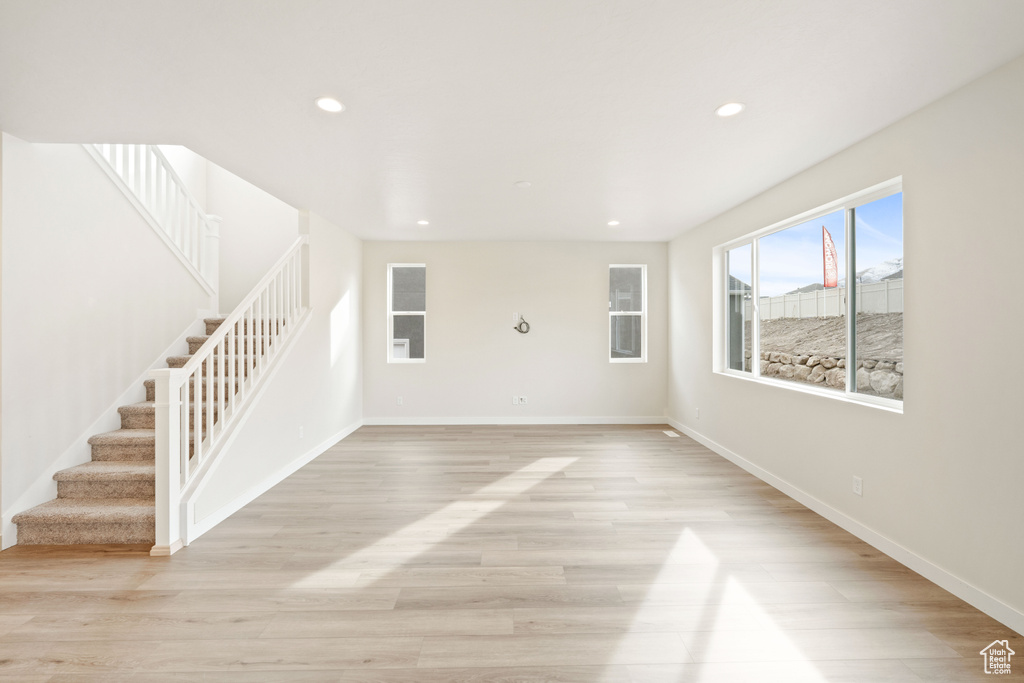 Unfurnished living room with stairway, recessed lighting, light wood-style floors, and baseboards