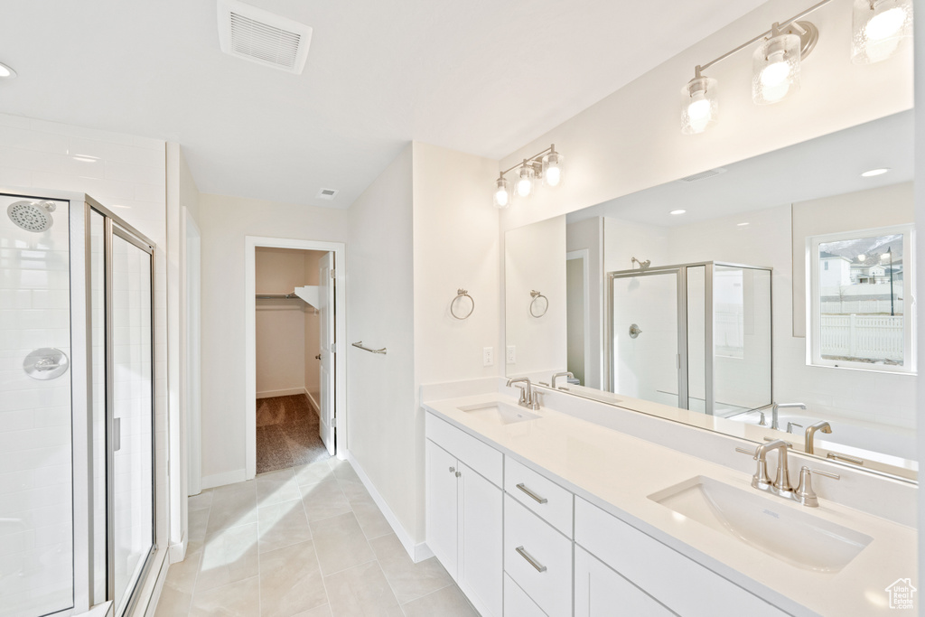 Full bathroom with a shower stall, double vanity, a spacious closet, a garden tub, and tile patterned floors