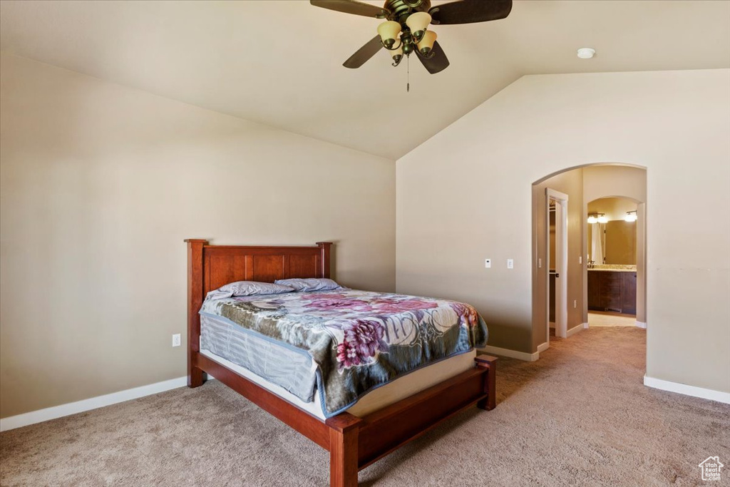 Carpeted bedroom featuring arched walkways, vaulted ceiling, baseboards, and ceiling fan