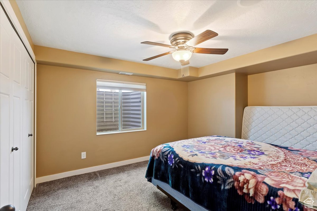 Carpeted bedroom featuring baseboards, a closet, and a ceiling fan