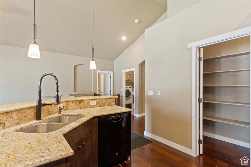 Kitchen featuring black dishwasher, a sink, washer / dryer, dark wood finished floors, and baseboards
