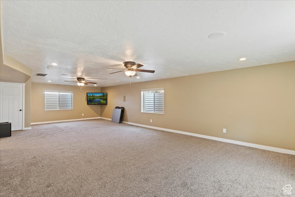 Carpeted empty room with a textured ceiling, a ceiling fan, baseboards, and recessed lighting