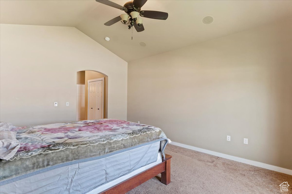Bedroom featuring arched walkways, vaulted ceiling, carpet, ceiling fan, and baseboards
