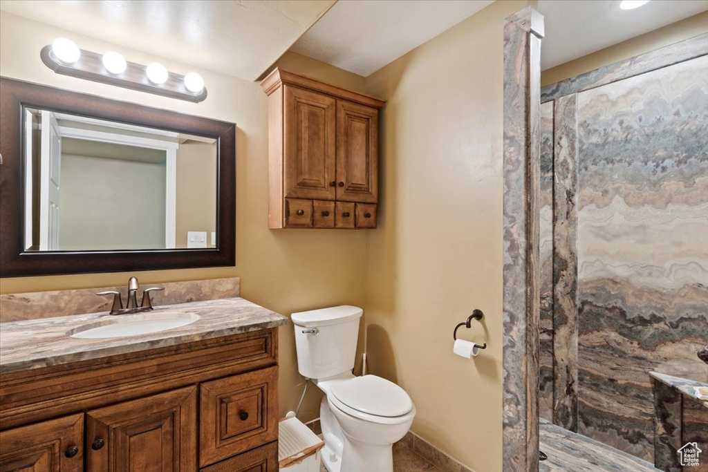 Bathroom featuring vanity, a walk in shower, toilet, and baseboards