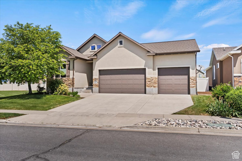 View of front facade featuring stucco siding, a garage, and stone siding