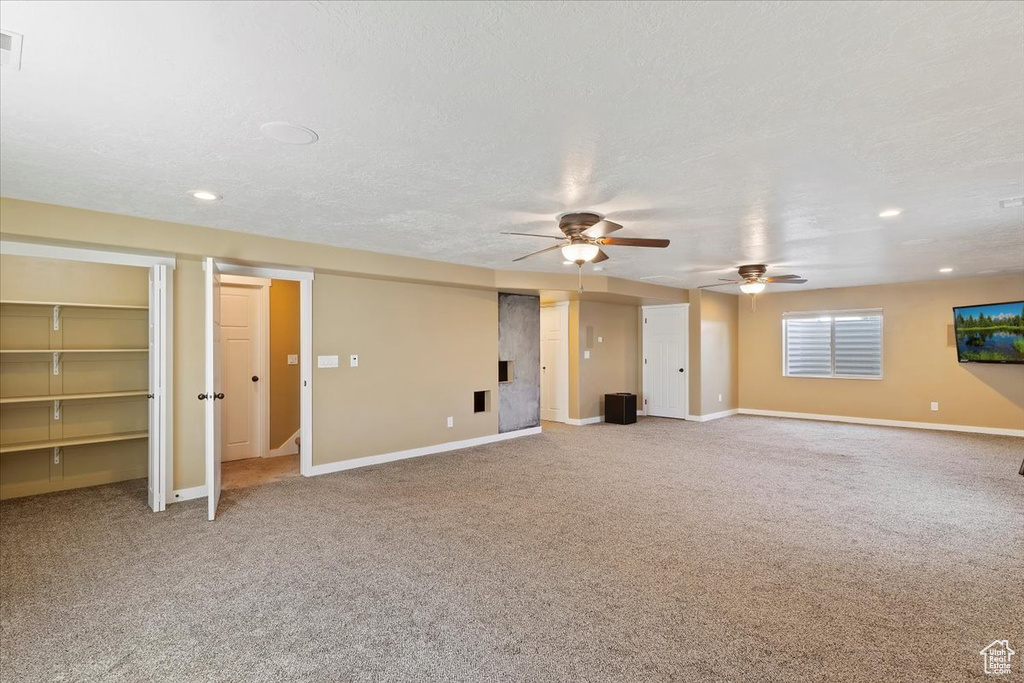 Unfurnished living room with carpet floors, a ceiling fan, baseboards, recessed lighting, and a textured ceiling