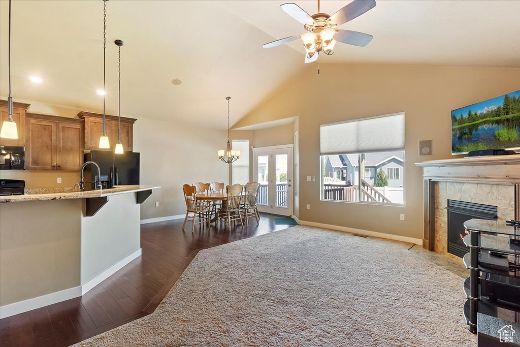 Kitchen featuring black fridge with ice dispenser, dark wood-style flooring, brown cabinetry, a fireplace, and baseboards