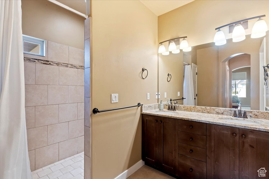 Full bath with double vanity and a tile shower