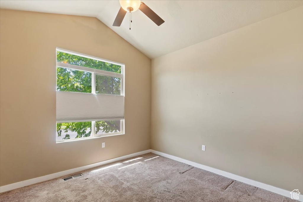 Carpeted spare room with ceiling fan, baseboards, and lofted ceiling