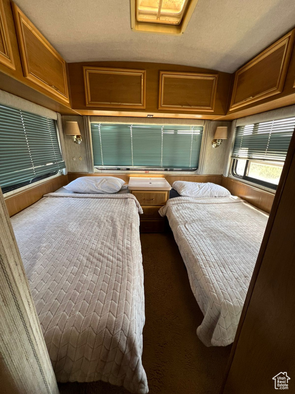 Bedroom with dark colored carpet, a textured ceiling, and vaulted ceiling