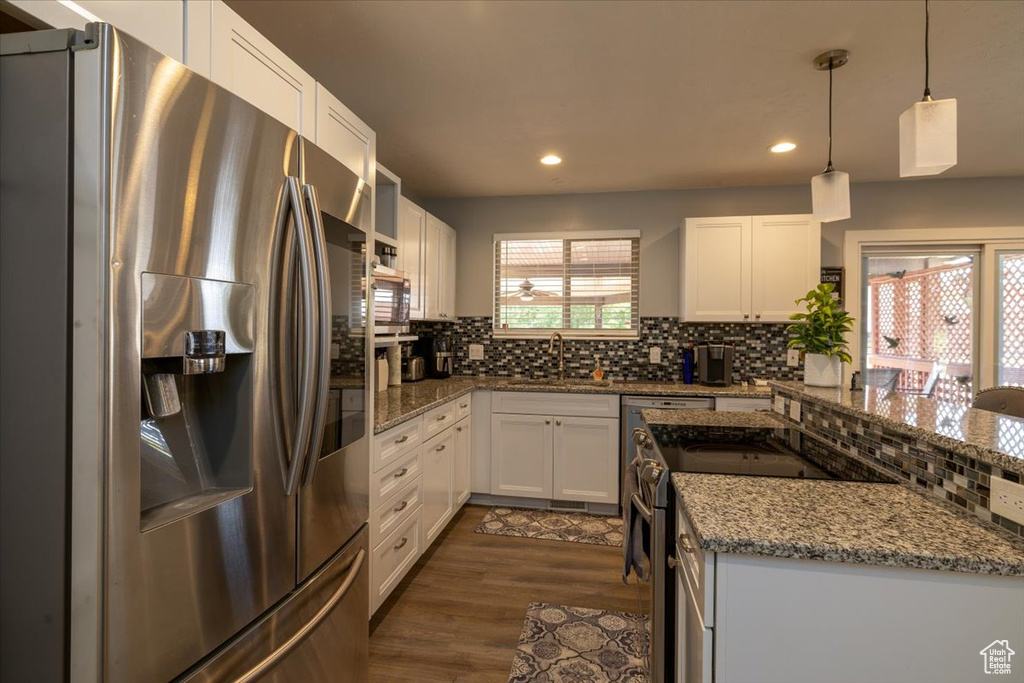 Kitchen with appliances with stainless steel finishes, tasteful backsplash, a sink, light stone counters, and recessed lighting