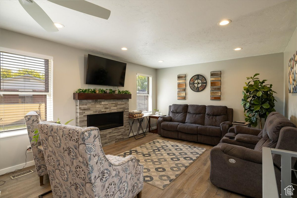 Living area with wood finished floors, recessed lighting, a stone fireplace, and baseboards