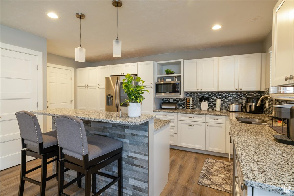 Kitchen featuring a sink, stainless steel appliances, a breakfast bar area, a center island, and white cabinets
