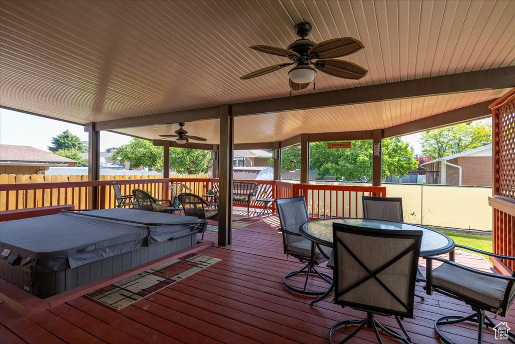 Wooden terrace with a covered hot tub, ceiling fan, and outdoor dining space