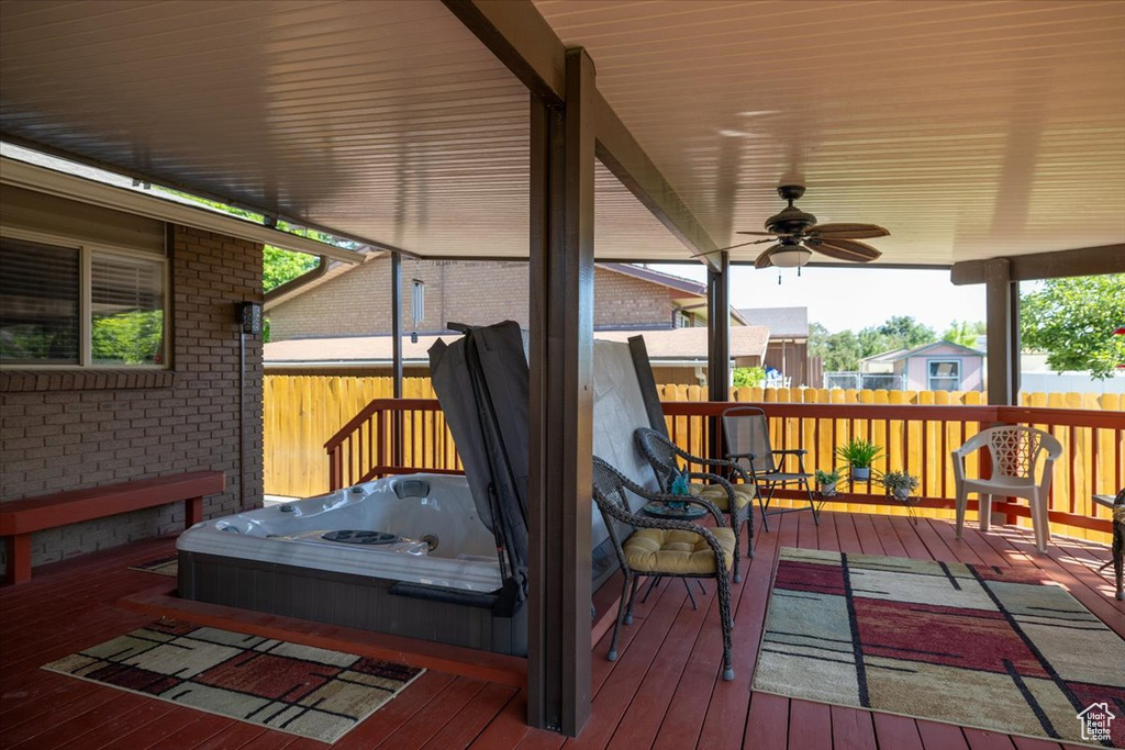 Wooden terrace featuring an outdoor hot tub and a ceiling fan