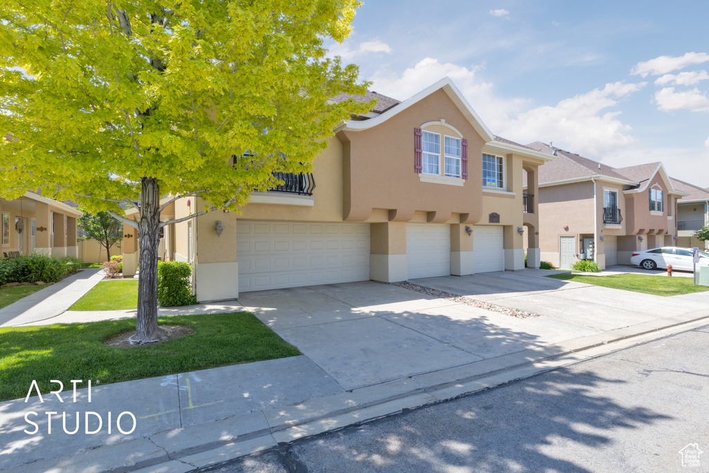 Multi unit property with stucco siding, a garage, concrete driveway, and a residential view