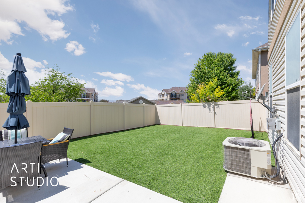 View of yard with central AC unit and a patio