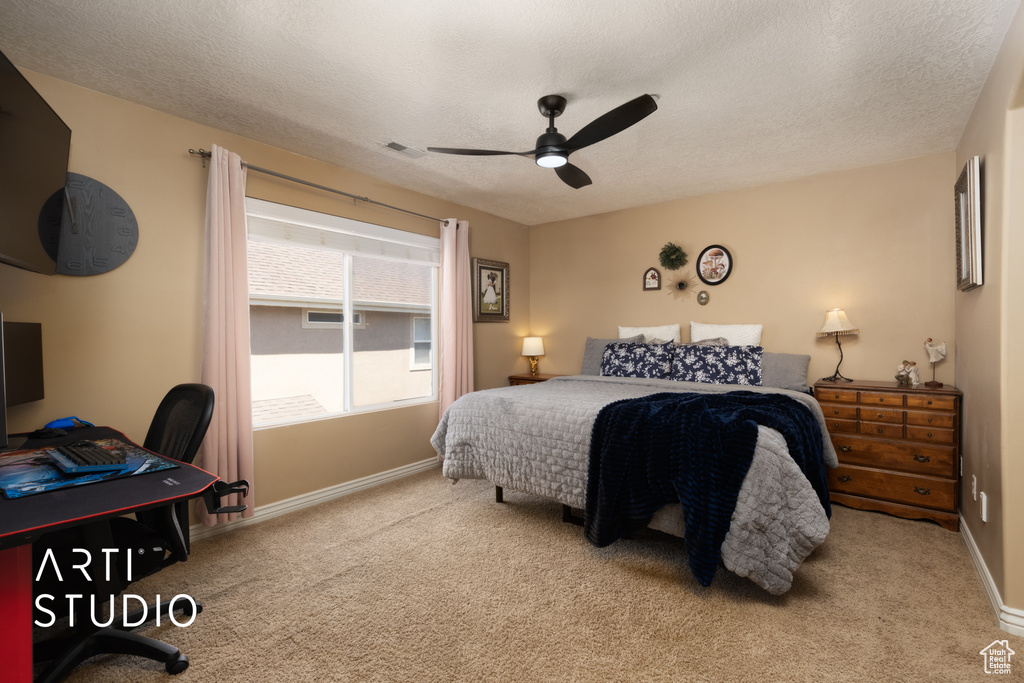 Carpeted bedroom with baseboards, a textured ceiling, ceiling fan, and an office area