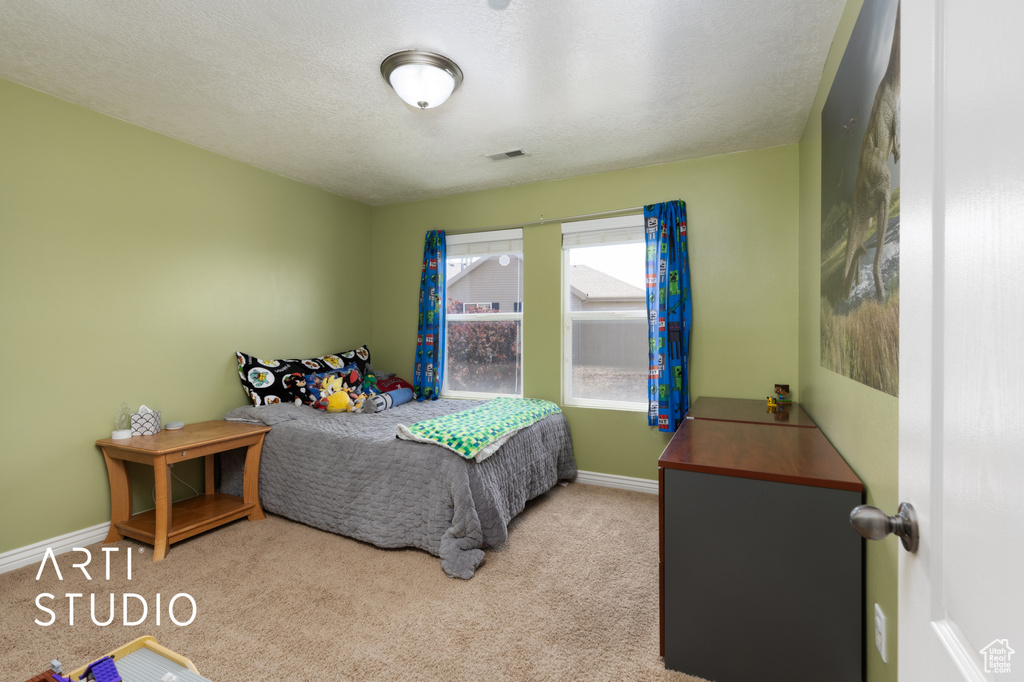 Bedroom with carpet flooring, baseboards, and a textured ceiling
