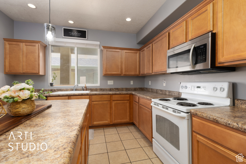 Kitchen featuring white electric range, stainless steel microwave, a sink, light tile patterned floors, and recessed lighting