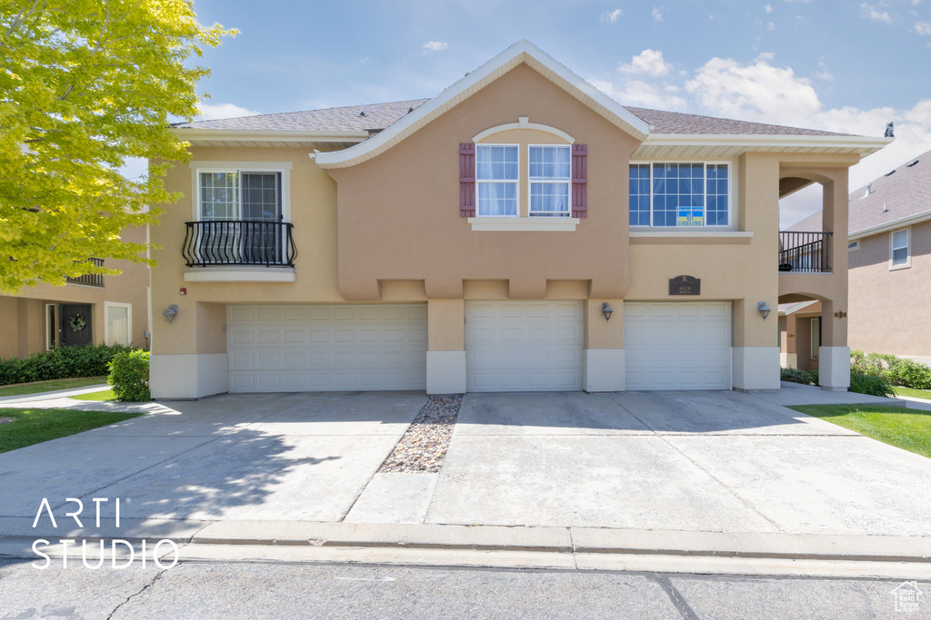 Townhome / multi-family property with driveway, an attached garage, and stucco siding