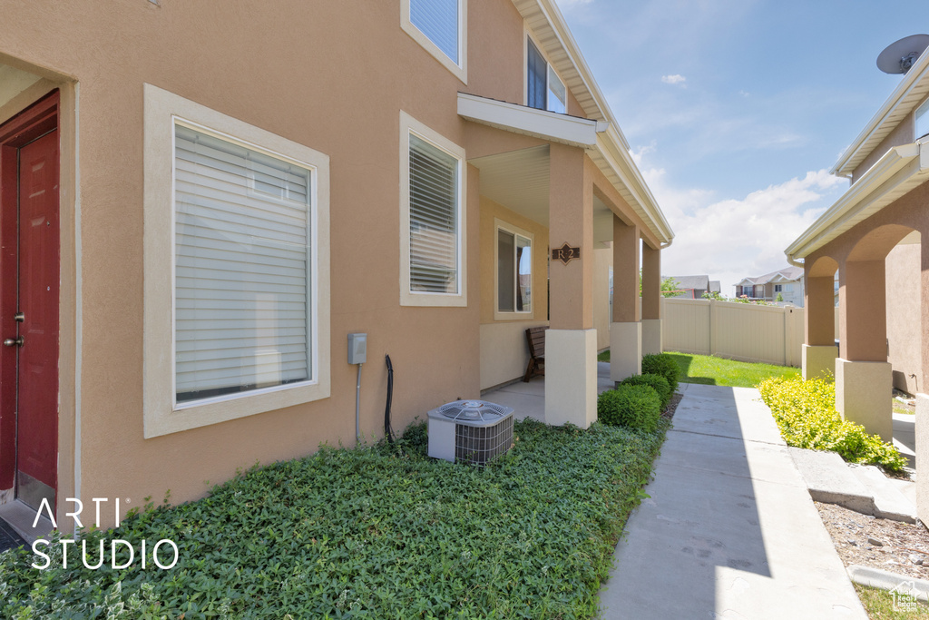 View of side of property with central AC unit, stucco siding, and a patio