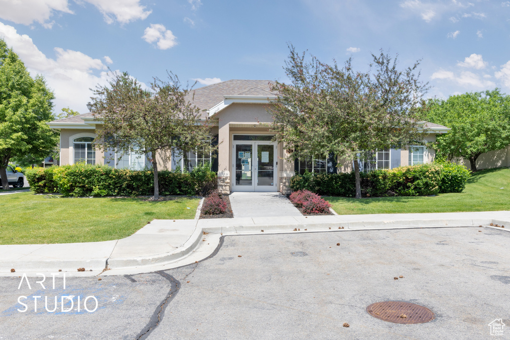 View of front of house with french doors, stucco siding, and a front yard